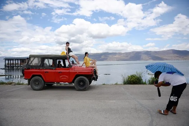 Women sit atop a vehicle as they pose for photos during a photoshoot session near Erhai Lake in Dali Bai Autonomous Prefecture, Yunnan province, China on June 15, 2019. (Photo by Tingshu Wang/Reuters)