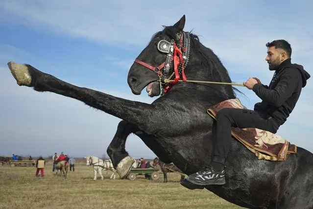 A man shows off riding skills during Epiphany celebrations in the village of Pietrosani, Romania, Thursday, January 6, 2022. According to the local Epiphany traditions, following a religious service, villagers have their horses blessed with holy water then compete in a race. (Photo by Vadim Ghirda/AP Photo)