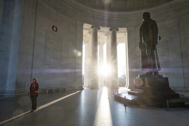 A tourist reads the inscriptions carved on the walls of the Jefferson Memorial as the early morning sun flares through the columns during the Presidents Day holiday, Monday, February 20, 2017, in Washington. (Photo by J. David Ake/AP Photo)
