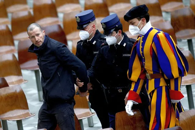Members of the gendarmerie and a member of the Pontifical Swiss Guard escort a man who interrupted Pope Francis' weekly general audience out, at the Vatican, February 2, 2022. (Photo by Guglielmo Mangiapane/Reuters)