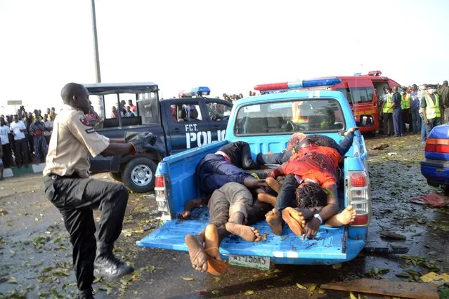 A man puts dead bodies, victims of an attack, in a car to be taken to the morgue in Abuja on April 14, 2014. Twin blasts at a bus station packed with morning commuters on the outskirts of Nigeria's capital killed dozens of people on April 14, in what appeared to be the latest attack by Boko Haram Islamists. (Photo by AFP Photo/STR)