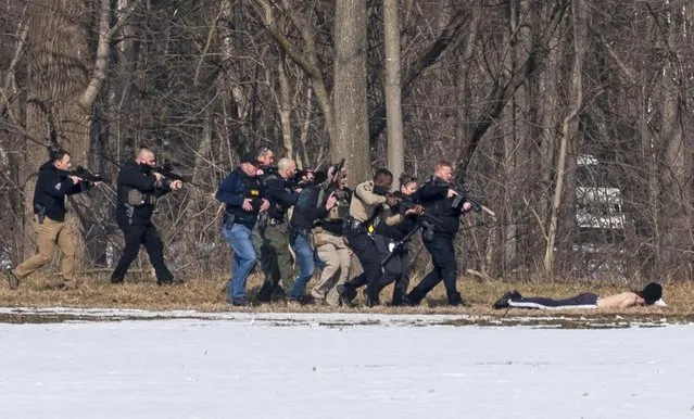 Police approach a suspect on the bank of the North River in Bridgewater, Virginia on February 1, 2022, after two campus police officers were shot at a college. (Photo by Daniel Lin/Daily News-Record via the AP Photo)