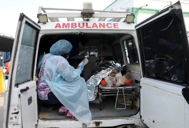 A nurse holds a drip next to a person injured when a fuel truck exploded in a neighbourhood during the night, in Cap Haitien, Haiti on December 14, 2021. (Photo by Ralph Tedy Erol/Reuters)