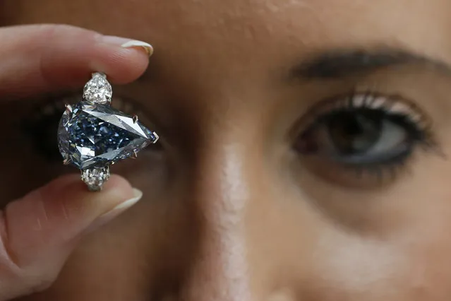 An employee poses with “The Blue” diamond at Christie's auction house in London April 29, 2014. Christie's London is displaying the largest flawless fancy vivid blue diamond ever to appear at auction. The diamond is pegged at $21 million to $25 million and is the highlight of an upcoming Magnificent Jewels sale in Geneva. (Photo by Stefan Wermuth/Reuters)