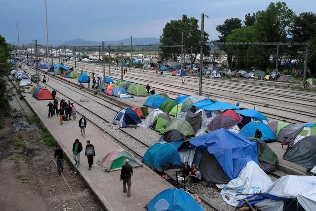 People walk past tents at a train station at a makeshift camp for migrants and refugees at the Greek-Macedonian border near the village of Idomeni, Greece, May 10, 2016. (Photo by Marko Djurica/Reuters)