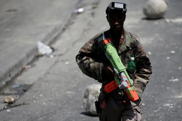 A man carrying a toy gun walks along a street blocked by barricades during a general strike day to protest against the shortage of fuel and against the government, in Port-au-Prince, Haiti, September 16, 2019. (Photo by Andres Martinez Casares/Reuters)