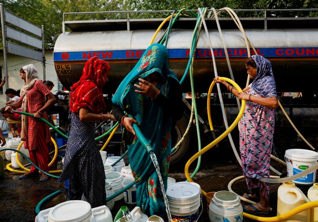 Residents use pipes to fill their containers with drinking water from a water tanker during a hot day in New Delhi, India, on June 24, 2024. (Photo by Priyanshu Singh/Reuters)