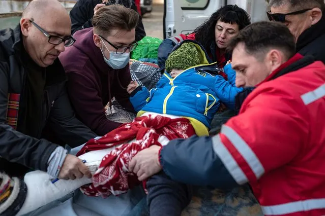 Medics move a boy from one stretcher to another before putting him in an ambulance car that would evacuate him to Poland on March 19, 2022 in Lviv, Ukraine. The evacuation programme removes sick children from the war in Ukraine and undertakes to match each child to a foreign hospital that has the capacity to continue their care. (Photo by Alexey Furman/Getty Images)