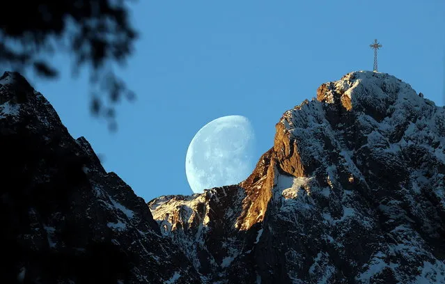 The moon sets behind the Great Giewont peak in the Tatra Mountains, in Zakopane, southern Poland, 23 March 2022. (Photo by Grzegorz Momot/EPA/EFE)