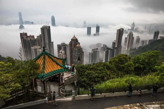 People gather at the Peak viewpoint to watch fog over Hong Kong on March 22, 2022. (Photo by Dale de la Rey/AFP Photo)