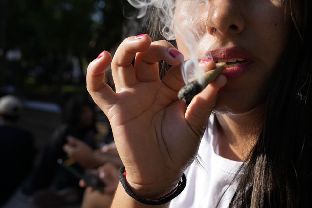 A youth smokes marijuana during the Open Plaza festival organized by the Granjamadre marijuana farm and the “Mama Cultiva” organization for medical marijuana in Asuncion, Paraguay, Sunday, April 23, 2023. (Photo by Jorge Saenz/AP Photo)