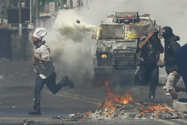 A man wearing a chef's hat runs for cover as anti-government protesters clash with police in Valparaiso, Chile, Thursday, October 24, 2019. (Photo by Matias Delacroix/AP Photo)