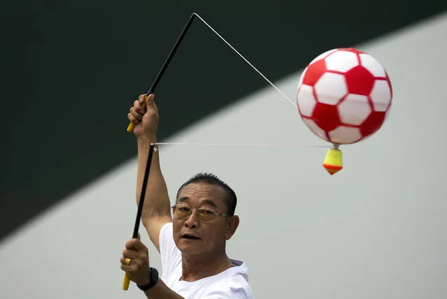 In this Sunday, June 28, 2015 photo, a man spins a top mount with an inflatable ball during a public sport campaign to promote exercise at Garden Expo Park in Beijing. (Photo by Andy Wong/AP Photo)