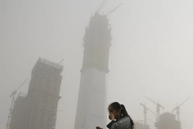 A woman covers her face by hands from polluted air and sandstorm in Beijing, Thursday, May 4, 2017. Authorities in Beijing issued a blue alert on air pollution as sandstorm swept through the Chinese capital city on Thursday morning. (Photo by Andy Wong/AP Photo)