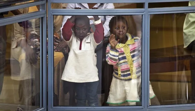 Two Kenyan children look out from an upper level in the reopened Westgate Shopping Mall, nearly two years after a terrorist attack there left at least 67 people dead, in the capital Nairobi, Kenya Saturday, July 18, 2015. Hundreds of shoppers thronged through the reopened mall Saturday, following two years of repairs after security forces battled four gunmen from Somalia's al-Qaida-linked al-Shabab militant group there in September 2013. (Photo by Ben Curtis/AP Photo)