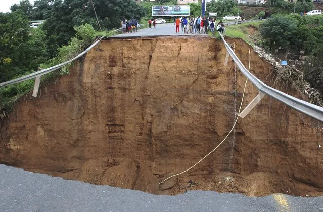 Stranded people stand in front of a bridge that was swept away in Ntuzuma, outside Durban, South Africa, Tuesday, April 12, 2022. Prolonged rains and flooding in South Africa's KwaZulu-Natal province have claimed dozens of lives, according to local officials. (Photo by AP Photo/Stringer)