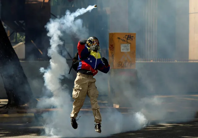 A demonstrator, wearing a jacket in the colours of the Venezuelan national flag, throws a tear gas canister during clashes with riot security forces at a protest against Venezuelan President Nicolas Maduro's government in Caracas, Venezuela May 30, 2017. (Photo by Carlos Garcia Rawlins/Reuters)