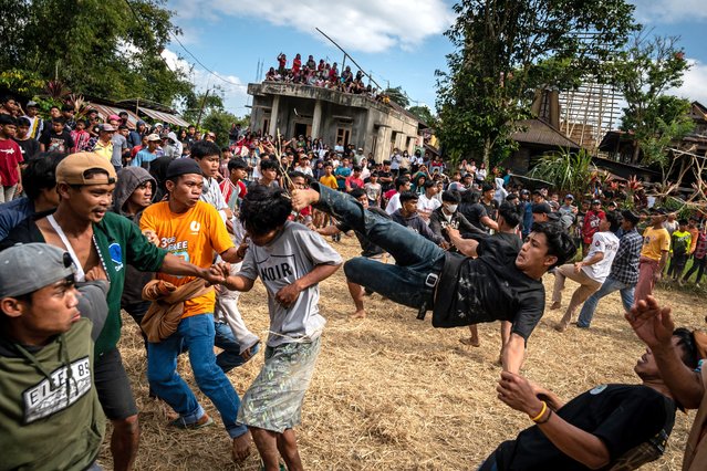 Men fight by kicking each other during their thanksgiving festival “Sisemba” after the rice harvest in Tikala, South Sulawesi, on August 11, 2024. Sisemba is performed by different age groups from neighbouring villages under the supervision of the elders, only they can kick or receive kicks while holding hands, and it is believed that the serious fight will bring another good harvest in the coming season. (Photo by Hariandi Hafid/AFP Photo)