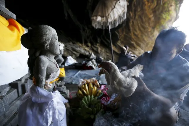 A Hindu villager holds a chicken as an offering while praying ahead of the annual Kasada festival at Mount Bromo in Indonesia's East Java province, July 30, 2015. (Photo by Reuters/Beawiharta)