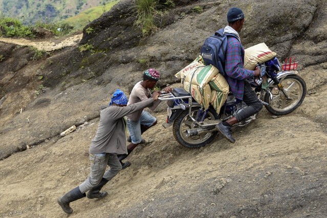 People help a motorcycle driver up a mountain to avoid gang violence in the Kenscoff neighborhood of Port-au-Prince, Haiti, Tuesday, September 10, 2024. (Photo by Odelyn Joseph/AP Photo)