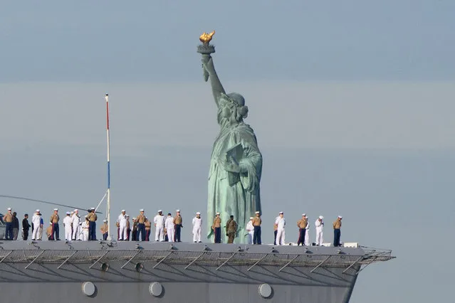 US Sailors and Marines stand on the flight deck of the USS Bataan as the ship passes the Statue of Liberty during Fleet Week in New York Harbor on May 25, 2022. (Photo by Angela Weiss/AFP Photo)