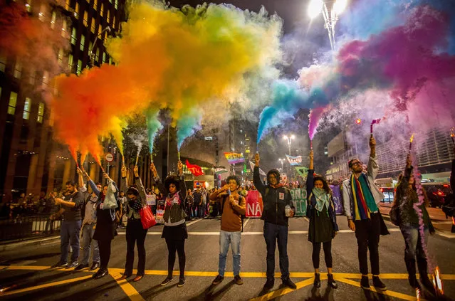Activists light up flares of the LGBT colors during a vigil in memory of victims of the mass shooting at the Pulse gay night club in Orlando, in Sao Paulo, Brazil on June 16, 2016. (Photo by ZUMA Wire/Rex Features/Shutterstock)