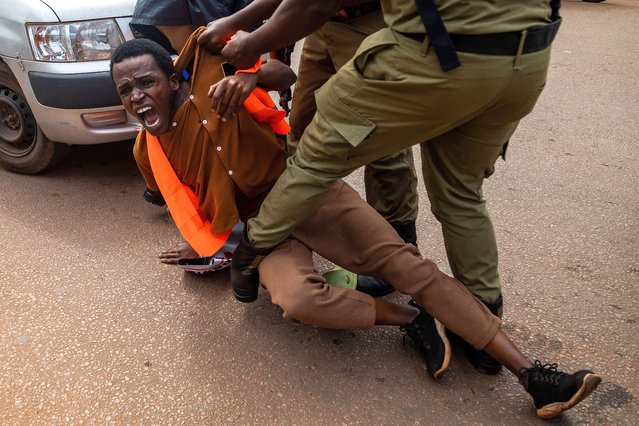 Ugandan police officers arrest an environmental activist taking part in a protest against the East African Crude Oil Pipeline Project (EACOP) in Kampala on August 26, 2024. Ugandan police arrested 21 environmentalists in the capital Kampala on August 26, 2024 as they protested a controversial multi-billion-dollar oil development scheme, their lawyer said. The East African Crude Oil Pipeline Project (EACOP), headed by French oil giant TotalEnergies, involves drilling for oil in Uganda and sending the crude to Tanzania for export. (Photo by Badru Katumba/AFP Photo)