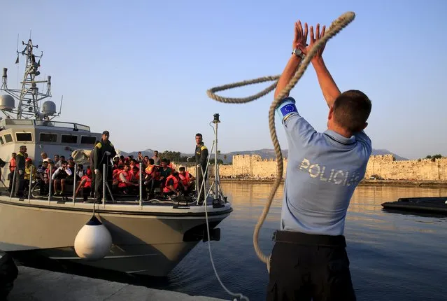 A Frontex officer grabs a rope thrown by Italian Coast Guard servicemen following a resque mission off the Greek island of Kos August 10, 2015. (Photo by Yannis Behrakis/Reuters)