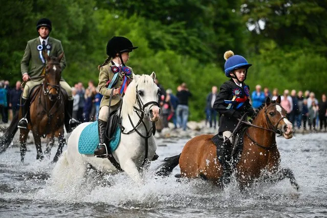 Riders ford the river Ettrick, as they take part in the town's Common Riding one of the oldest Borders festivals on June 17, 2022 in Selkirk, Scotland. In the centuries-old tradition, a cavalcade of horsemen and women ride the town's boundaries, echoing a practice from the late Middle Ages when there were frequent raids on the Anglo-Scottish border. (Photo by Jeff J. Mitchell/Getty Images)