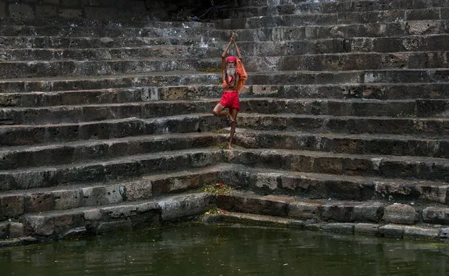 A Sadhu or Hindu holy man performs yoga on the steps of Saubhagya Kund, a holy pond, at the Kamakhya temple in Gauhati, India, Tuesday, June 23, 2015. Hundreds of Sadhus, or Hindu holy men, have arrived for the five-day festival to perform rituals at the temple during the annual Ambubasi festival that began Monday. (Photo by Anupam Nath/AP Photo)