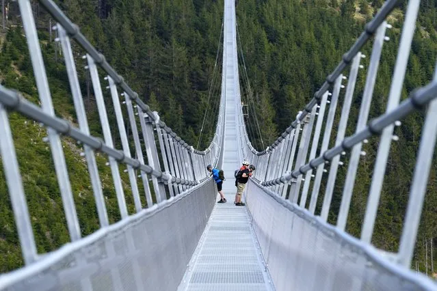People stand on a suspension bridge for the pedestrians that is the longest such construction in the world a day before its official opening at a mountain resort in Dolni Morava, Czech Republic, Thursday, May 12, 2022. The 721-meter (2,365 feet) long bridge is built at the altitude of more than 1,100 meters above the sea level. It connects two ridges of the mountains up to 95 meters above a valley between them. (Photo by Petr David Josek/AP Photo)