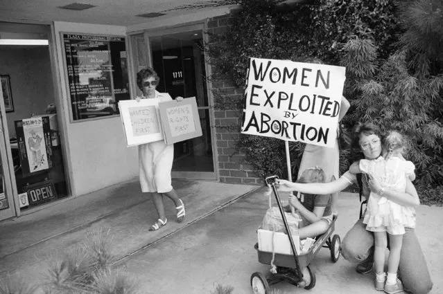 Dr. Lynn Negus, left, an associate clinical professor at the University Of Southern California School Of Medicine, holds two small pro-abortion signs, after she demonstrated recently at a building entrance where a coalition of anti-abortion groups marched against an alleged abortion practitioner in Torrance, Calif. on August 27, 1985. At right, Debbie Thyfault and her children, Heidi, 6, and Hansi, 4, hold an anti-abortion sign. (Photo by Wally Fong/AP Photo)