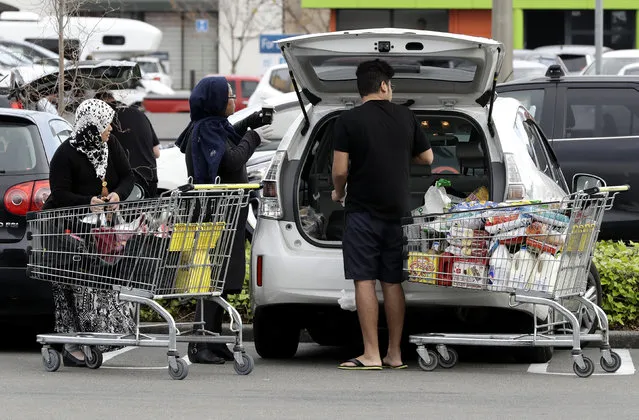 A family packs its shopping into their car in a supermarket in central Christchurch, New Zealand, Monday, March 23, 2020. New Zealand Prime Minister Jacinda Ardern announced the country would be going into full lockdown for about four weeks starting Wednesday. That prompted whoops and tears from school children, office workers to begin hauling computers and plants to their cars, and snaking lines to form in supermarkets, where shoppers stripped shelves bare of coffee, flour and toilet paper. (Photo by Mark Baker/AP Photo)