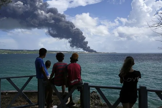 People watch a huge rising plume of smoke caused by a blaze at the Matanzas Supertanker Base, in Matazanas, Cuba, Saturday, August 6, 2022. (Photo by Ramon Espinosa/AP Photo)
