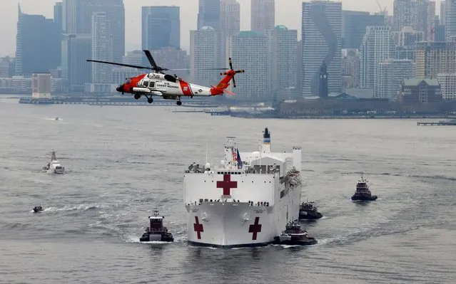 A U.S. Coast Guard helicopter flies above USNS Comfort as it enters New York Harbor during the outbreak of the coronavirus disease (COVID-19) in New York City, U.S., March 30, 2020. (Photo by Mike Segar/Reuters)