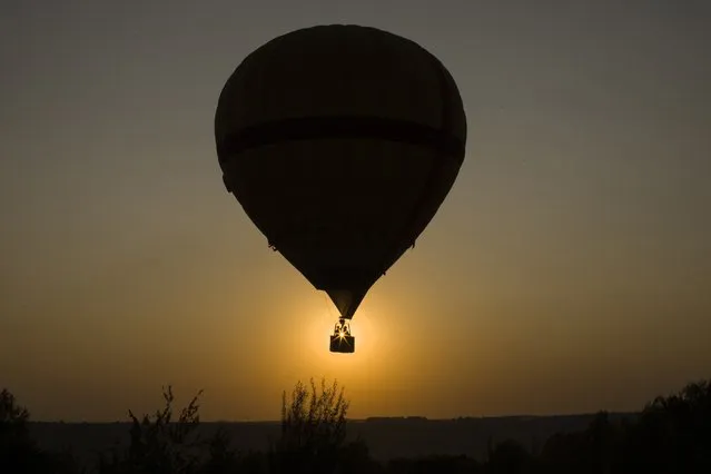 A couple enjoys a a hot-air balloon flight over the Peremilovo village, 65 km (40 miles) north of Moscow, during the sunset Sunday, August 20, 2017. The temperature jumped to 32 degrees Celsius, 89,6 Fahrenheit today. (Photo by Alexander Zemlianichenko/AP Photo)