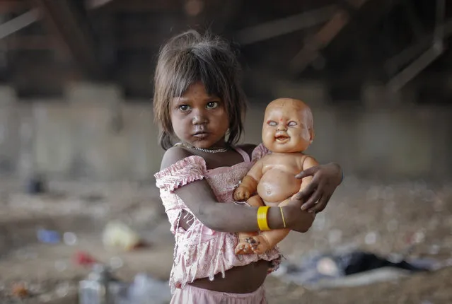 A homeless girl plays with her doll under a bridge in Mumbai November 27, 2012. (Photo by Danish Siddiqui/Reuters)