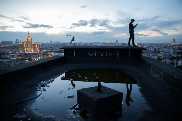 Sergii Rodionov takes a photograph on his mobile phone from a rooftop in Moscow, Russia, June 2, 2017. (Photo by Maxim Shemetov/Reuters)