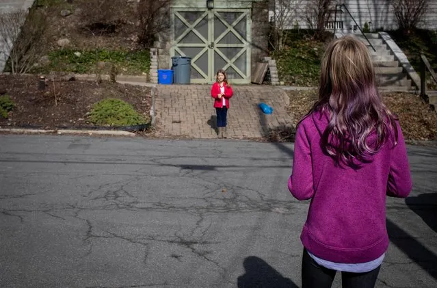 Friends and neighbors, Sarah and Elizabeth, talk about their weekends from opposite sides of the road as they maintain social distance in a neighborhood in Syracuse, New York, U.S., April 5, 2020 amid a coronavirus disease (COVID-19) outbreak. (Photo by Maranie Staab/Reuters)