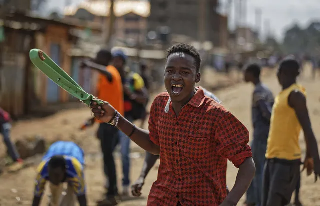 An opposition supporter uses a slingshot to launch stones at police during clashes in the Kawangware area of Nairobi, Kenya, Saturday, October 28, 2017. Kenyan opposition areas were generally calmer Saturday, though clashes between supporters of opposition leader Raila Odinga and police continued in Kawangware, and it was still not clear when the presidential election, a rerun of the flawed vote in August, would be over. (Photo by Ben Curtis/AP Photo)