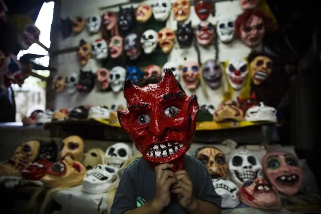 A boy wears a devil's mask as he poses for a photograph in a craft workshop for masks during the celebration of the “Los Agüizotes” in Masaya, Nicaragua, 27 October 2017. Hundreds of people dressed as characters from the ancestral legends of Nicaraguan and as all sort of “ghosts” and depictions of “death” seized the town of Masaya, south east of Managua, in the traditional “Los Agüizotes” festival which is annually celebrated on the last Friday in October and - as Nicaraguans are stressing – has nothing to do with the better known “Halloween” Day. (Photo by Jorge Torres/EPA/EFE)