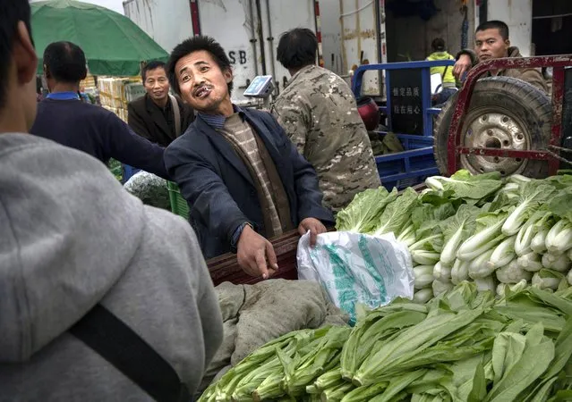 A Chinese vendor makes a deal with a customer at a local market on September 26, 2014 in Beijing, China. (Photo by Kevin Frayer/Getty Images)