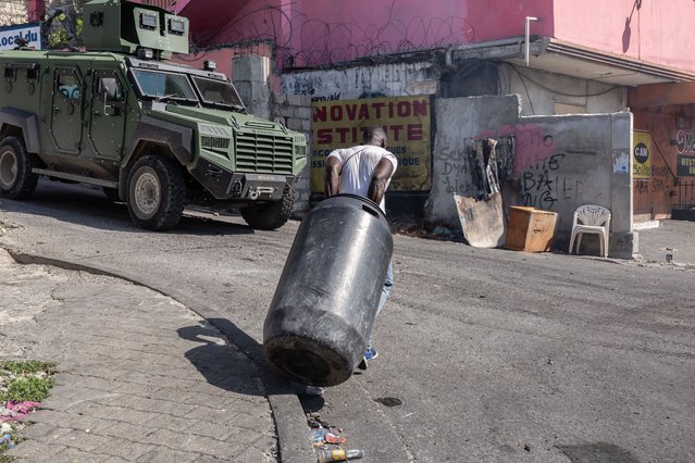 A man passes in front of an armored tank carrying belongings after the fire caused by armed gangs in the street of Port-au-Prince, as the Solino neighborhood fall under control of armed gangs, which formed in February and worked to oust former Haitian Prime Minister Ariel Henry, who resigned from his post in April, in Port-au-Prince, Haiti, on November 16, 2024. The crisis affecting Solino and the surrounding area, as well as Vivy Mitchel, illustrates once again the powerlessness of the authorities to protect the urban populations of Port-au-Prince, leaving thousands of families violence and insecurity. (Photo by Guerinault Louis/Anadolu via Getty Images)