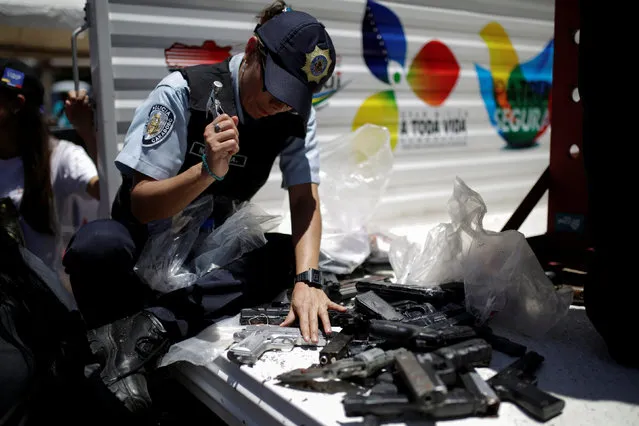 A police officer hammers a pistol during an exercise to destroy seized weapons in Caracas, Venezuela August 17, 2016. (Photo by Marco Bello/Reuters)