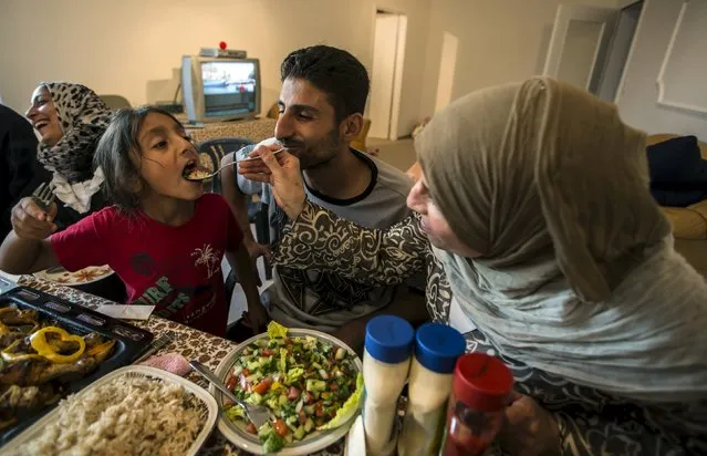 Yasmine, 6, a Syrian migrant from the Syrian city of Deir al-Zor, is fed by her grandmother as her father Ihab looks on, during a welcoming dinner at her house upon their arrival in Lubeck, Germany September 18, 2015. Picture taken September 18, 2015. (Photo by Zohra Bensemra/Reuters)