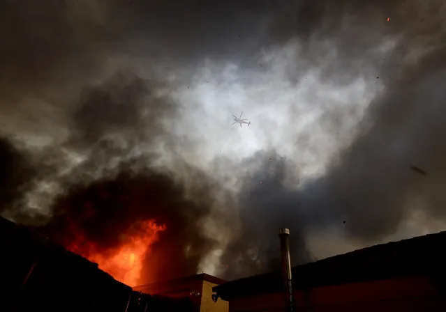 A water dropping helicopter flies over a hot spot on the Creek Fire in the Lake View Terrace area of Los Angeles, Tuesday, December 5, 2017. (Photo by Chris Carlson/AP Photo)