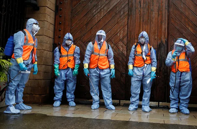 Municipal workers wearing personal protective equipment (PPE) wait to enter the residence of Bollywood actor Amitabh Bachchan to sanitize it after he and his son, actor Abhishek Bachchan, tested positive for the coronavirus disease (CIVID-19), in Mumbai, India, July 12, 2020. (Photo by Francis Mascarenhas/Reuters)