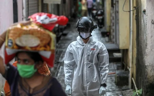 An Indian health worker wearing smart helmet walks after conducting the thermal screening of residents of a slum in Mumbai, India, 14 July 2020. Countries around the world are still taking measures to stem the spread of the SARS-CoV-2 coronavirus which causes the COVID-19 disease and have intensified their research for treatment. (Photo by Divyakant Solanki/EPA/EFE)