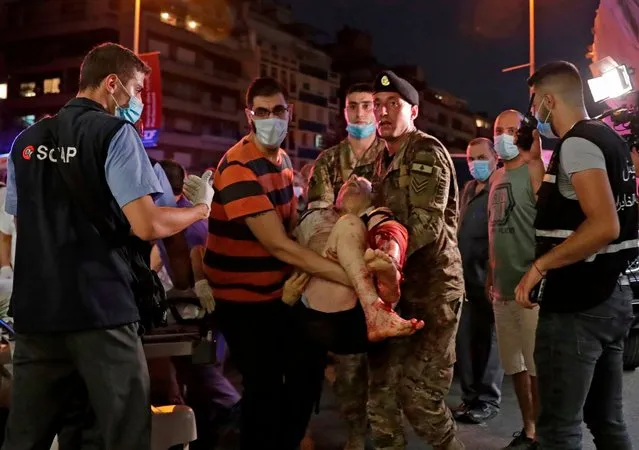 Lebanese army soldiers carry away an injured man at a hospital in the aftermath of an explosion at the port of Lebanon's capital Beirut on August 4, 2020. Two huge explosion rocked the Lebanese capital Beirut, wounding dozens of people, shaking buildings and sending huge plumes of smoke billowing into the sky. Lebanese media carried images of people trapped under rubble, some bloodied, after the massive explosions, the cause of which was not immediately known. (Photo by Ibrahim Amro/AFP Photo)