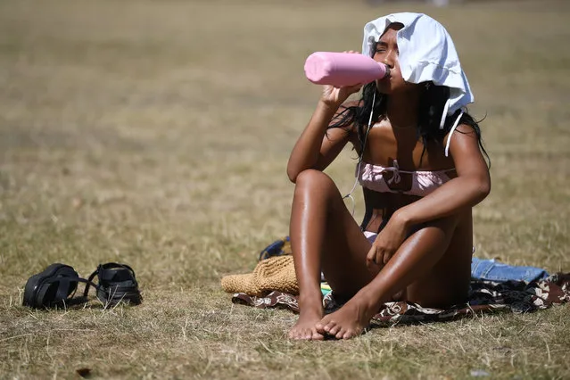 A woman cools her self as she sunbathes in St James' Park in London, Britain 07 August 2020. Britain is in the midst of a heatwave which ​could see record breaking temperatures according to some media reports. (Photo by Neil Hall/EPA/EFE)